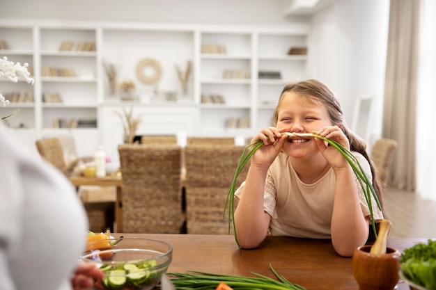 Foto gratuita cerrar niña sonriente sosteniendo cebolla verde