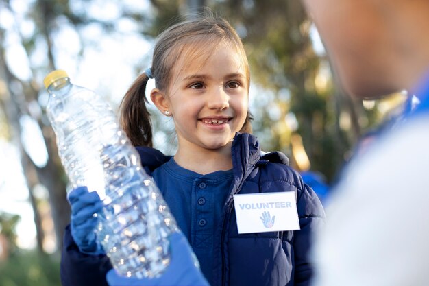 Cerrar niña sosteniendo una botella de plástico