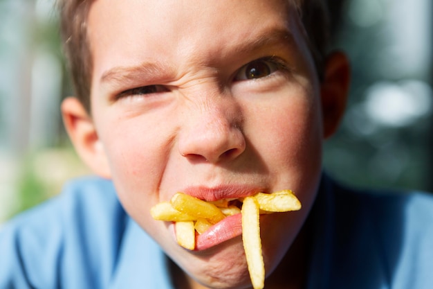 Cerrar niño comiendo papas fritas