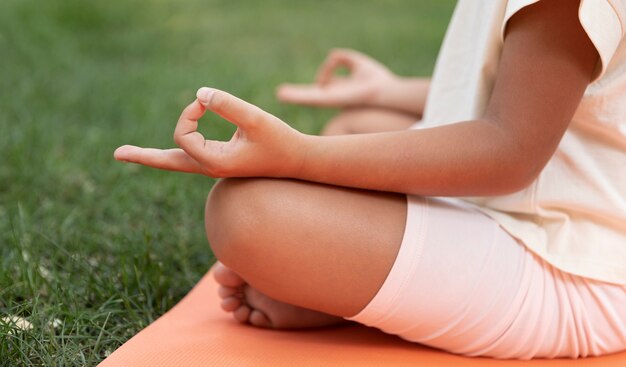 Cerrar niño meditando al aire libre