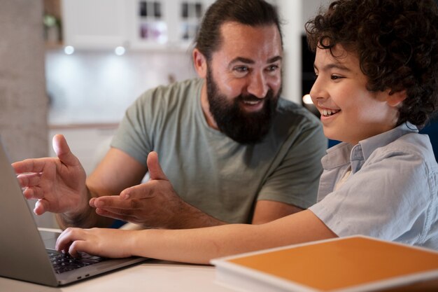 Cerrar el niño mirando por encima de la computadora portátil con los padres
