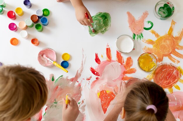 Cerrar a los niños pintando con pinceles juntos