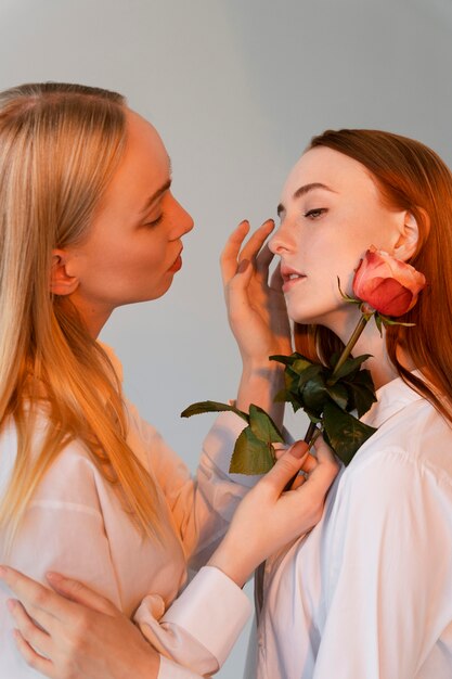 Cerrar pareja de mujeres posando con rosa