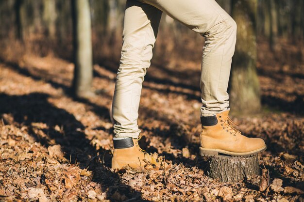 Cerrar las piernas en los zapatos de rastreo del hombre hipster que viaja en el bosque de otoño, turista activo, explorando la naturaleza en la estación fría, calzado