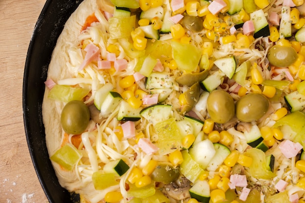 Cerrar pizza cruda en sartén con ingredientes