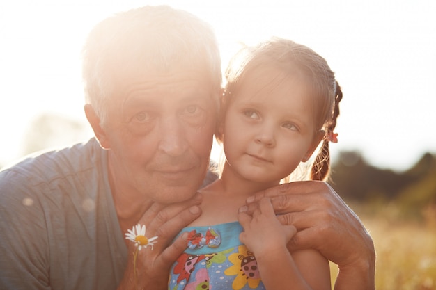 Cerrar retrato de abuelo canoso abraza con amor pequeña nieta, tener relaciones veraces