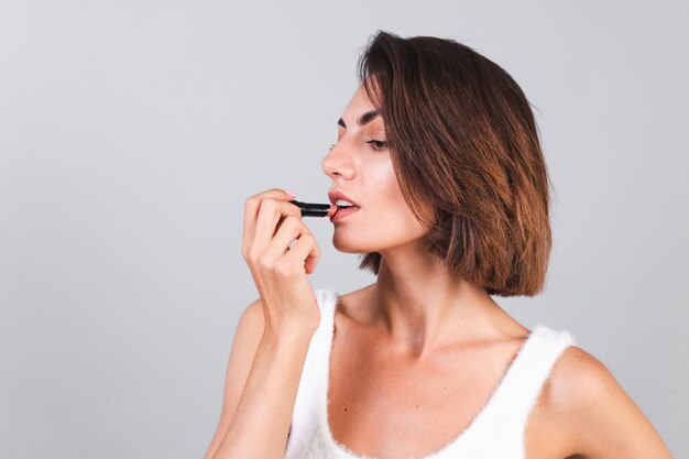 Cerrar retrato de belleza de mujer con maquillaje y lápiz labial marrón en pared gris