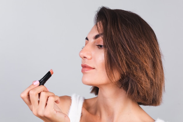 Cerrar retrato de belleza de mujer con maquillaje y lápiz labial marrón en pared gris