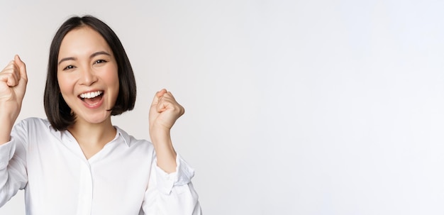 Cerrar el retrato de la cara de una mujer asiática bailando sonriendo triunfando y celebrando con emoción feliz