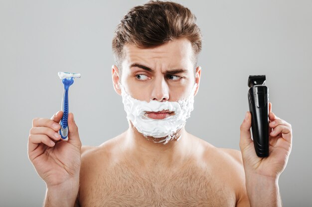 Cerrar el retrato de un hombre confundido con espuma de afeitar