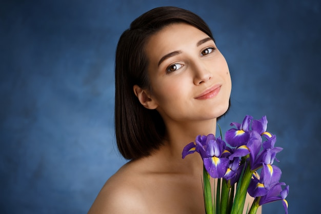 Cerrar retrato de joven tierna con iris violeta sobre pared azul