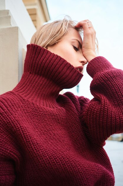 Cerrar sensual chica rubia en suéter de punto posando emocionalmente al aire libre