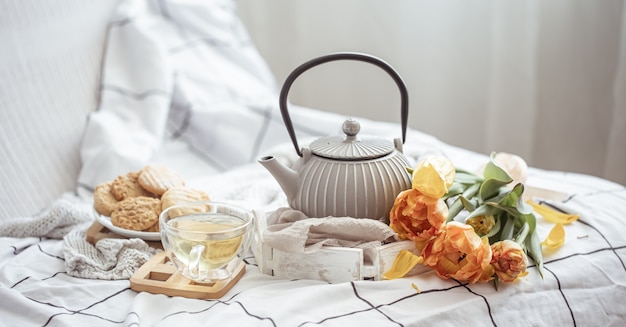 Cerrar té, galletas y un ramo de tulipanes frescos en la cama