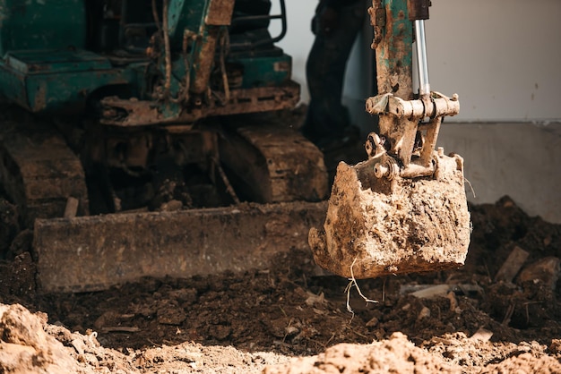 Cerrar trabajador retroexcavadora trabajando en sitio de construcción