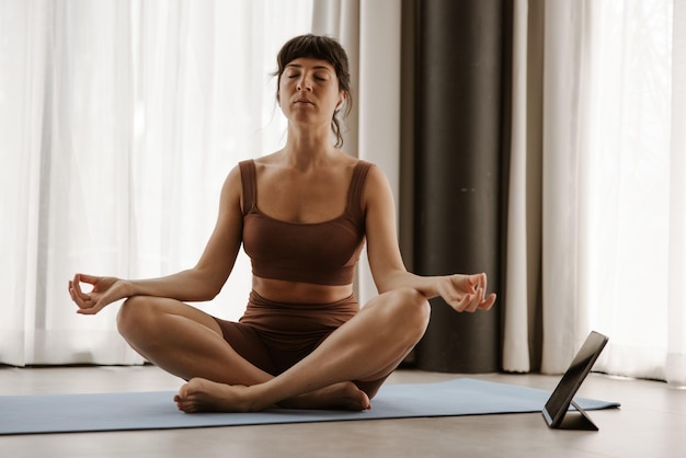 Cerrar vista de deportistas haciendo yoga en la computadora portátil con los ojos cerrados