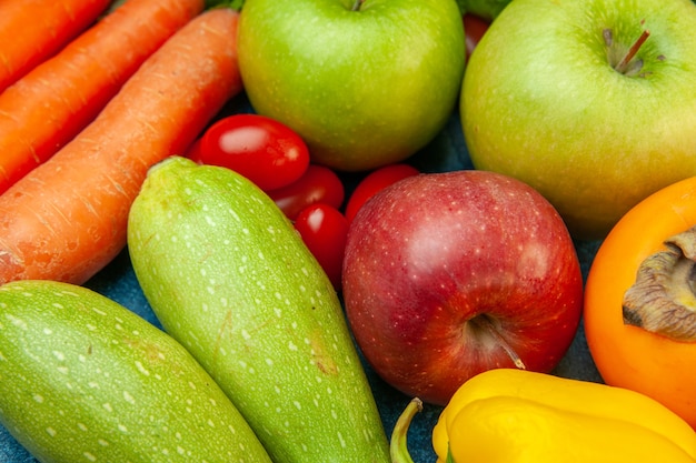 Cerrar vista inferior frutas y verduras tomate cherry manzana caqui calabacín zanahoria en mesa azul