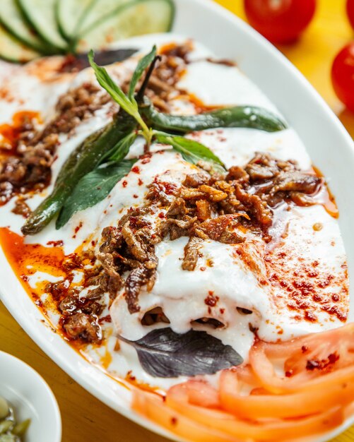 Cerrar vista de kebab iskender turco servido con yogurt agrio en plato blanco