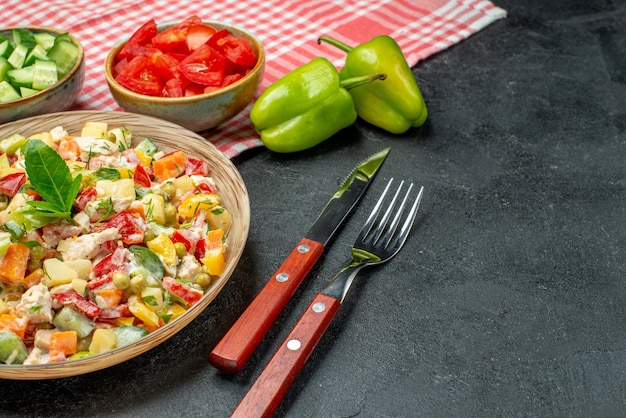 Foto gratuita cerrar vista lateral de ensalada de verduras con cubiertos vegetales y servilleta roja sobre fondo gris oscuro