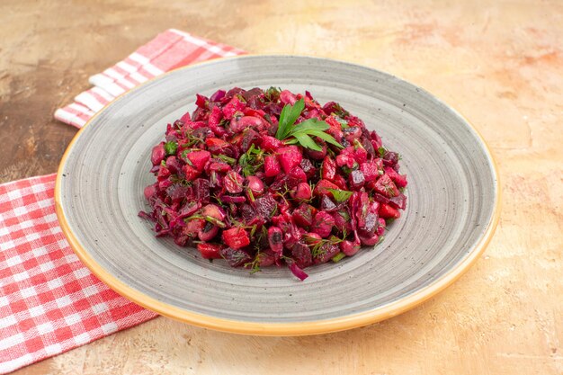 Cerrar vista lateral del plato de una ensalada roja con verduras con una servilleta marcada en el lateral sobre un fondo de madera