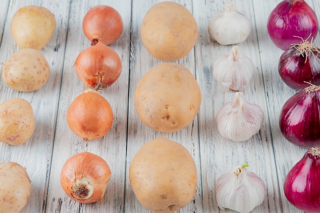 Cerrar vista de patrón de verduras como cebolla patata ajo sobre fondo de madera