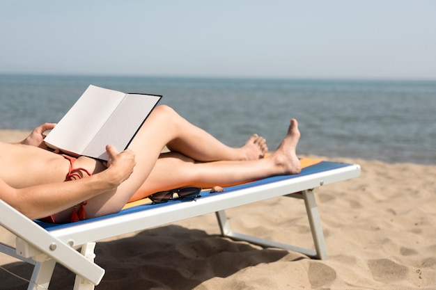 Foto gratuita cerrar vista posterior mujer en silla de playa leyendo