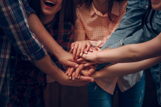 Cerrar vista superior de amigos juntando sus manos en la fiesta de cumpleaños