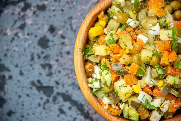 Cerrar vista superior ensalada de verduras hervidas dentro de la placa sobre fondo azul.