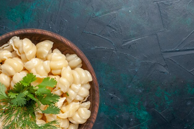 Cerrar vista superior pasta de masa cocida con verduras dentro de la placa sobre una superficie oscura