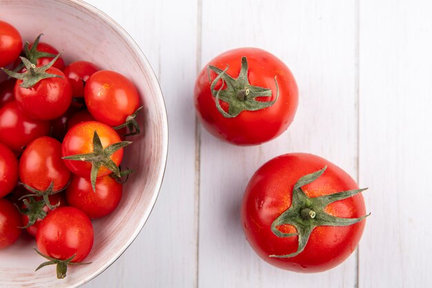 Cerrar vista de tomates en un tazón y sobre superficie de madera