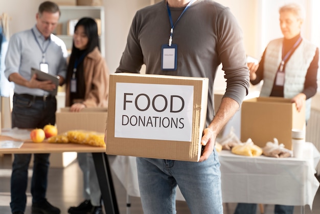 Foto gratuita cerrar voluntario sosteniendo la caja de donaciones de alimentos