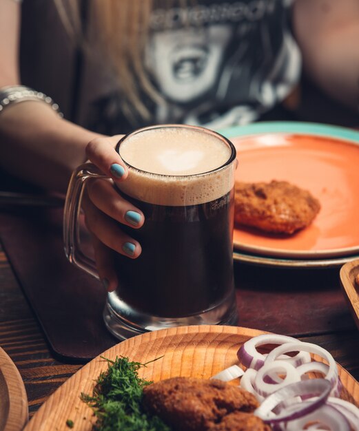 Cerveza negra en taza con pollo frito sobre la mesa