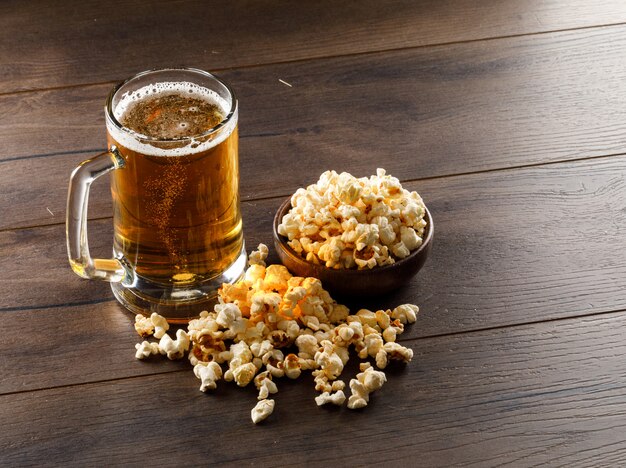 Cerveza en una taza de vidrio con palomitas de maíz alto ángulo de vista sobre una mesa de madera