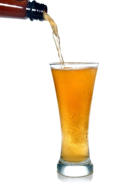 Cerveza vertiendo de botella en vidrio aislado en blanco