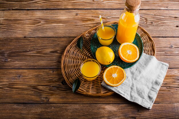 Cesta de alto ángulo con botella y vaso de jugo de naranja