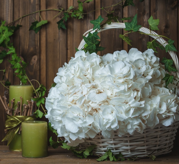 Cesta de flores blancas como la nieve con velas verdes alrededor