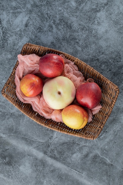 Cesta de frutas de madera con manzanas y melocotones rojos