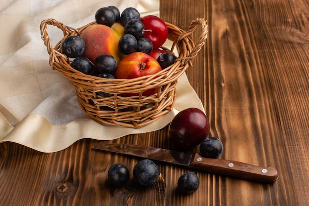 Cesta con frutis endrinos ciruelas y melocotones sobre madera