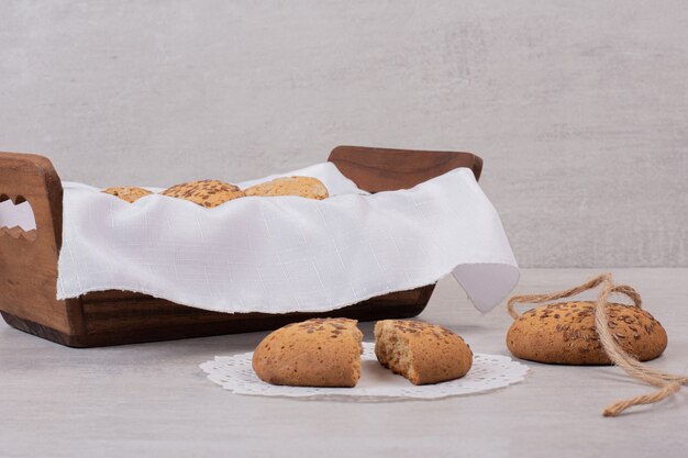 Cesta de galletas con semillas de sésamo sobre superficie blanca.