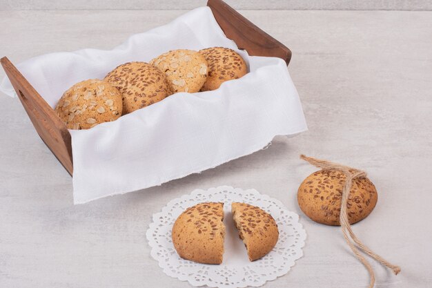 Cesta de galletas con semillas de sésamo sobre superficie blanca.