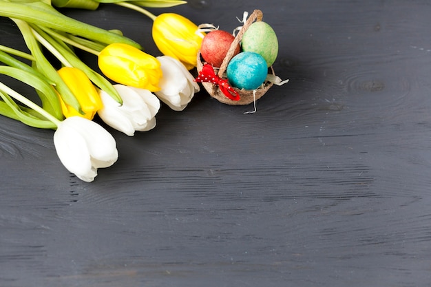 Cesta con huevos cerca de ramo de tulipanes