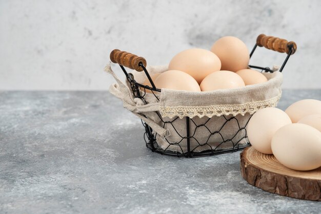 Cesta de huevos crudos frescos orgánicos colocados sobre la superficie de mármol.