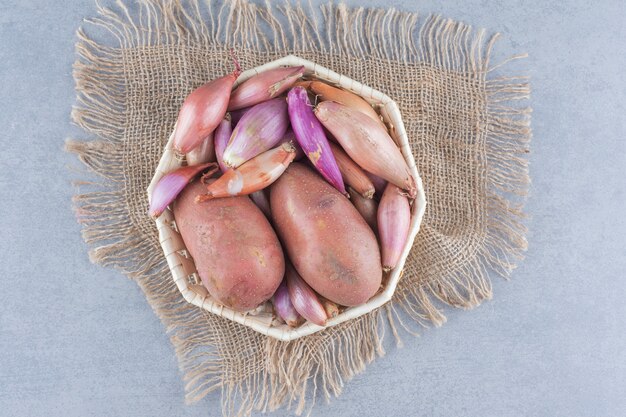 Cesta llena de patatas y cebollas.