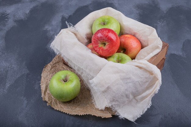 Foto gratuita cesta de manzanas de colores en la oscuridad.