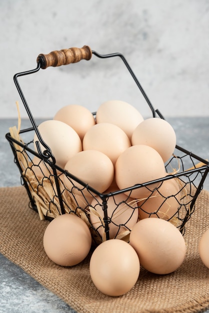 Foto gratuita cesta metálica de huevos de gallina cruda sobre superficie de mármol.