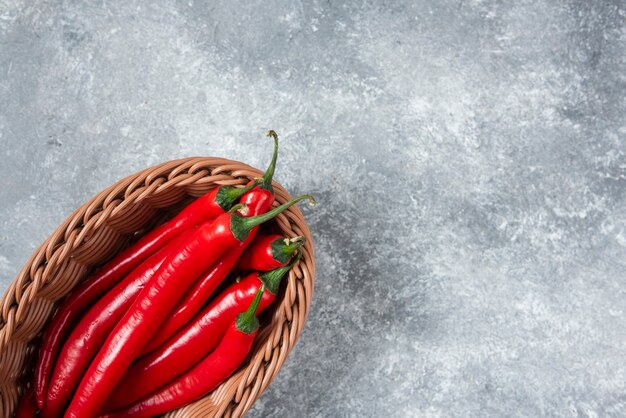 Cesta de mimbre de chiles rojos sobre superficie de mármol.