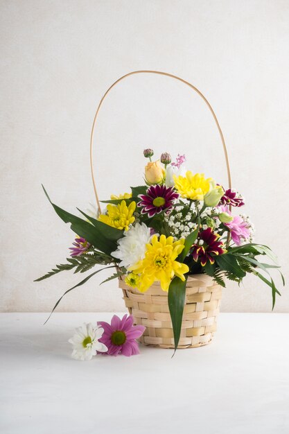 Cesta de mimbre con flores colocadas en el escritorio.