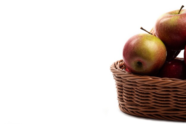 Cesta de mimbre de jugosas manzanas frescas aisladas en blanco.