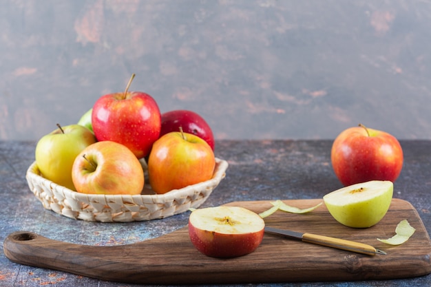 Cesta de mimbre de manzanas frescas de colores sobre la mesa de mármol.