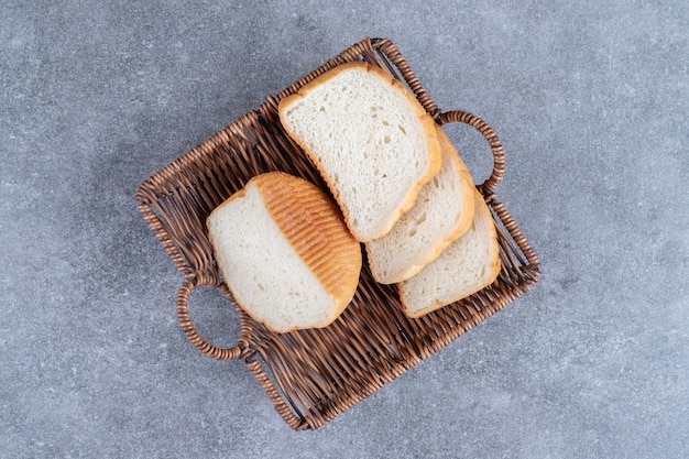 Cesta de mimbre de pan blanco en rodajas colocado sobre la mesa de piedra.