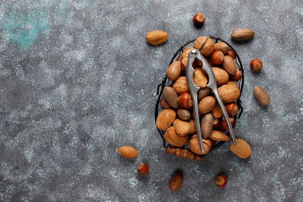 Cesta de nueces surtidas y herramienta para romper tuercas sobre mármol